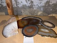 Six geode pieces including five flat polished slices with natural banding in various colors.