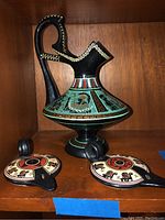 Large black and painted Greek jug with handle and pedestal, decorated with mythological scenes and Greek key pattern.