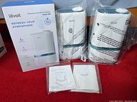 Photo showing two unpacked Levoit humidifiers wrapped in plastic with power cables and manuals, next to boxed third unit.