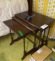 Three Ethan Allen nesting side tables stacked, showing spindle legs, dark brown wood finish, and blue tape markings on largest and medium tops.