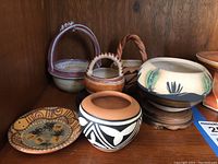 Overview of 5 Southwest inspired pottery items including various pots and a plate on a wooden shelf