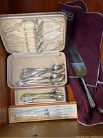 Overview of case with spoons, two boxes of forks and serving knife in cloth pouch