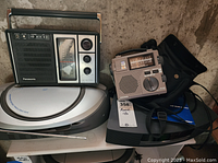 Shelf with Panasonic portable radio, Grundig FR-200 world band receiver, Bose Wave music system and Sony boombox.