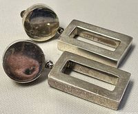 Top and side view of both earrings showing circular base and rectangular hollow section with patina and signs of wear