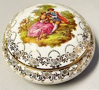 Closed view of the Limoges bone china trinket box lid showing hand-painted romantic couple and gold floral design.