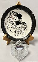 Front view of vintage signed pottery ashtray depicting two clowns in black and white.