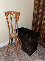 Plant stand and basket shown side by side on carpeted floor against beige wall