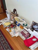 Photo showing a collection of craft items including printed cross stitch patterns, skeins of yarn in a cloth tote bag, and a handmade woven purse with a letter 'P'.