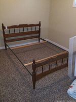 Full view of the solid wood double bed frame showing headboard, footboard, and metal rails on carpeted floor.