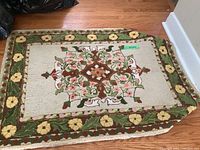 Full view of hand hooked floor mat with central floral medallion and border of yellow flowers and green leaves.