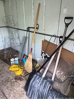 Photo showing snow shovels, broom, rakes, extension cord, tomato cages, garden fencing and garden supplies in shed