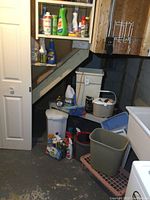 Photo showing resin shelf stocked with various cleaning products and other items underneath a staircase.