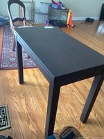 Full side view of the black rectangular expanding table showing the legs and surface.