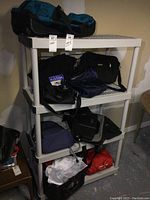 Shelf holding various black hand bags, backpacks, and travel bags.