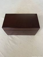 Closed view of the dark polished wooden jewelry box, rectangular with smooth finish.