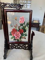Front side of the Chinese double-sided embroidery table screen showing pink and red peonies with butterflies and berries in dark wooden stand.