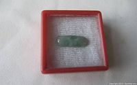 View of the jadeite ring top in a display box with a padded white background, showing size and containment.