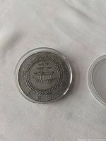 Obverse side of the coin showing a traditional Chinese pavilion surrounded by writing in Chinese characters. Coin is in a protective plastic capsule.