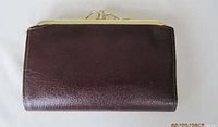 Closed view of dark brown leather vintage lady's clutch wallet with metal clasp closure at the top.