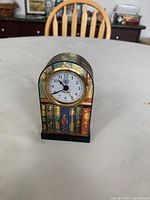 Front view of the quartz clock showing the clock face and decorative book spine design