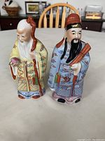 Front view of two Chinese porcelain Star Gods figurines with detailed painting, one in yellow robes and the other in blue.