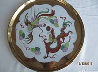 Top view of the round porcelain tray showing dragon and phoenix motifs in colorful paint with a gold border.