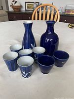 Full view of the vintage Japanese sake set including 2 decanters and 7 cups arranged on a table.