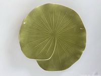 Top view of green lily pad shaped ceramic dish with embossed veins and minor wear