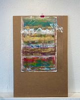 Full view of the abstract painting on a brown backing board with plastic protective cover.