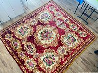 Full view of the vintage Italian rug laid flat on a wooden floor showing full floral design and borders.