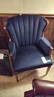 Overall front view of the wing back chair showing upholstery and wood frame style.