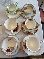 Top view of six distinct tea cups and saucers showing varied floral patterns and some gold trim.