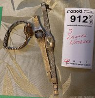 Photo showing three ladies watches laid flat with a MaxSold lot tag indicating 3 ladies watches.