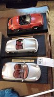 Three Porsche model cars displayed on a table, showing the full lot.