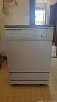 Front view of white freestanding portable dishwasher with faux wood top and control panel