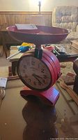 Red vintage scale with two clock faces visible and a weighing tray on top.