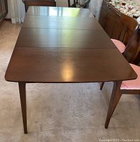 Top-down view showing the full rectangular surface of the dark stained wood table with two visible section lines where leaves attach.