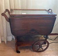 Front view of entire tea cart showing glass top tray, drop leaves and wheel configuration