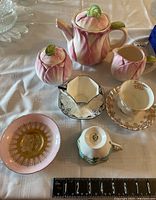Full tea set with cups, saucers, sugar bowl, creamer, and teapot on white cloth.