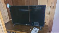 Front view of black RCA flat screen TV with instruction manual on table.
