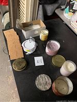 Photo showing various candles, cork coasters, textured coasters, and mug warmer box arranged on dark surface.