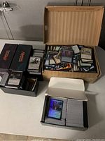Four boxes of assorted Magic: The Gathering cards arranged on a table. Visible cards include foil variants.
