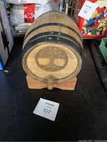Front view of a mini wood barrel keg showing decorative tree design on the end, with wooden spigot and stand