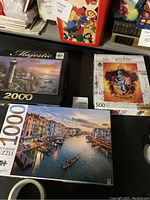 Photo shows three boxed jigsaw puzzles: Harry Potter Gryffindor 500pc, Venice canal 1000pc, Majestic 2000pc.