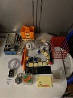 Photo showing a table with multiple older stationary items including boxed Acrobat Puzzle, Mac speakers, calculator, desk organizers, protractor and hourglass.