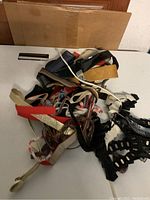 Top-down view of assorted women's belts piled together showing variety in color, material, and style.