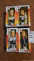 Four Team Canada hockey bobble heads in original boxes featuring players Iginla, Foote, Joseph and coach Gretzky, each dressed in their respective outfits.