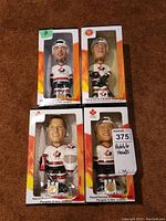 Four hand painted Team Canada hockey bobblehead dolls in original boxes, displayed together showing the front of packaging and artwork