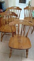 Four oak chairs from slightly above and side angle showing the seat, legs and spindle backs.