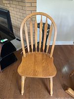 Single wooden spindle-back dining chair showing seat, legs and vertical slats on backrest